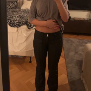 Svarta byxor - Snygga svarta byxor med en tight passform. Perfekta för en stilren look och kan enkelt matchas med olika toppar. Byxorna har en klassisk design med knapp och dragkedja framtill. Och väldigt lågmidjade 