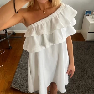 Superfin vit klänning  - Otroligt fin one-shoulder klänning med stora volanger från COCOMORE boutique, perfekt till studenten eller sommaren!🤍 Storlek 36 men passar både större och mindre. Den har insydda fickor på sidorna (som nästan inte syns), jättebra kvalité och fint skick!! Går att bära på flera olika sätt🌟tryck gärna på ”köp nu”