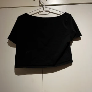 Svart croppad topp - Säljer en stilren svart croppad topp från H&M. Toppen har korta ärmar och en rund halsringning, perfekt för en trendig look. Passar utmärkt till både jeans och kjol.