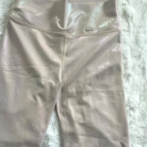 Glittriga cykelbyxor från Aim'n - Snygga glittriga cykelbyxor/korta leggings från Aim'n i en ljusrosa/skimmrig nyans. De har en hög midja och är perfekta för att ge en extra touch till din outfit. Materialet är stretchigt och bekvämt, vilket gör dem idealiska för både träning och vardag. Aldrig använda, endast testade! Jättemjuka och sitter fint på!