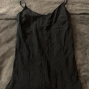 Svart linne från 157 - Snyggt svart linne från 157 i storlek S. Tillverkad av 95% bomull och 5% elastan för en bekväm passform. Perfekt för en stilren look med smala axelband.