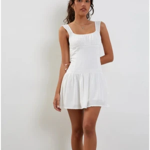 Vit kortklänning med volangdetaljer - Säljer en söt vit kortklänning med volangdetaljer. Klänningen har breda axelband och en fyrkantig urringning. Perfekt som studentklänning! Den e från Motelrocks och endast använd en gång. Köpt för 700 nypris.