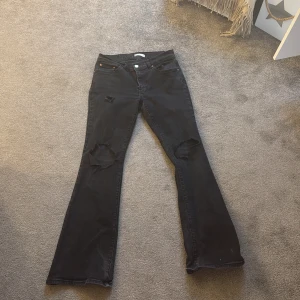 Svarta bootcut jeans med slitningar - Snygga svarta bootcut jeans med coola slitningar på knäna.  Hålen har jag klippt själv!