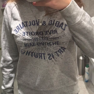 Grå sweatshirt med tryck - Säljer en grå sweatshirt med ett stort blått tryck på framsidan. Tröjan har långa ärmar och en rund halsringning. Perfekt för en avslappnad stil.