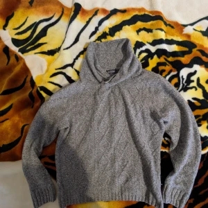 Grå stickad polotröja från Dressmann - Säljer en stilren grå stickad polotröja från Dressmann. Tröjan har en klassisk design med långa ärmar och ribbade muddar. Perfekt för kyligare dagar och ger en snygg look. Passar bra till både jeans och chinos.