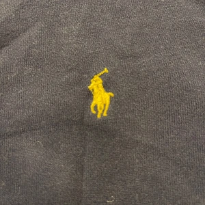 Mörkblå hoodie från Ralph Lauren - Säljer en klassisk mörkblå hoodie från Ralph Lauren med dragkedja och gul logotyp.  Den har en bekväm passform och praktiska fickor framtill. Barn storlek alltså lite mindre. Pris kan diskuteras 💕