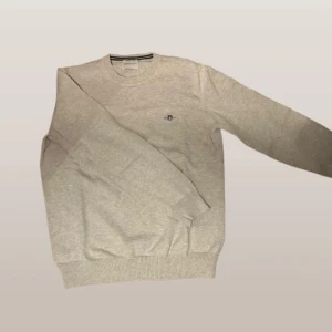 Cotton crew neck tröja från GANT - Säljer en stilren light beige tröja från GANT med rund hals och broderad logga på bröstet. Perfekt för en avslappnad och snygg look. Tröjan har långa ärmar och ribbade muddar vid ärmslut och nederkant. Pris kan absolut diskuteras!✨