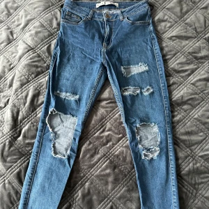 Blå jeans med slitningar - Blå ripped jeans köpta i London. Mycket stretchiga, high waist.