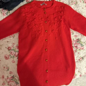 Röd broderad kofta - Söt, röd, oanvänd kofta, väldigt gosig och varm med fina broderade rosor på. 