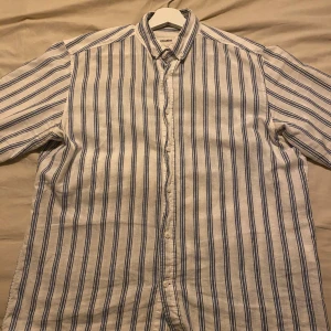 Vitblå randig skjorta - Säljer den vitblå randiga skjorta från Pull & Bear som är använd men i bra skick. Perfekt för vardaglig användning men också för fest. Den passar som en medium. 