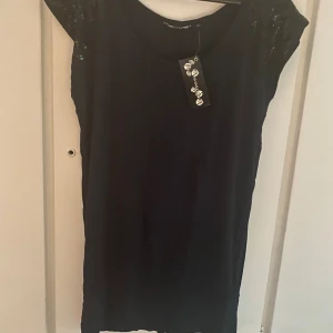 Blus - Svart t-shirt med paljetter på axlarna. Aldrig använd.