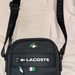 lacoste väska  - säljer denna väskan eftersom jag har köpt en ny och behöver ingen mer användning av den, och den är even i perfekt skick