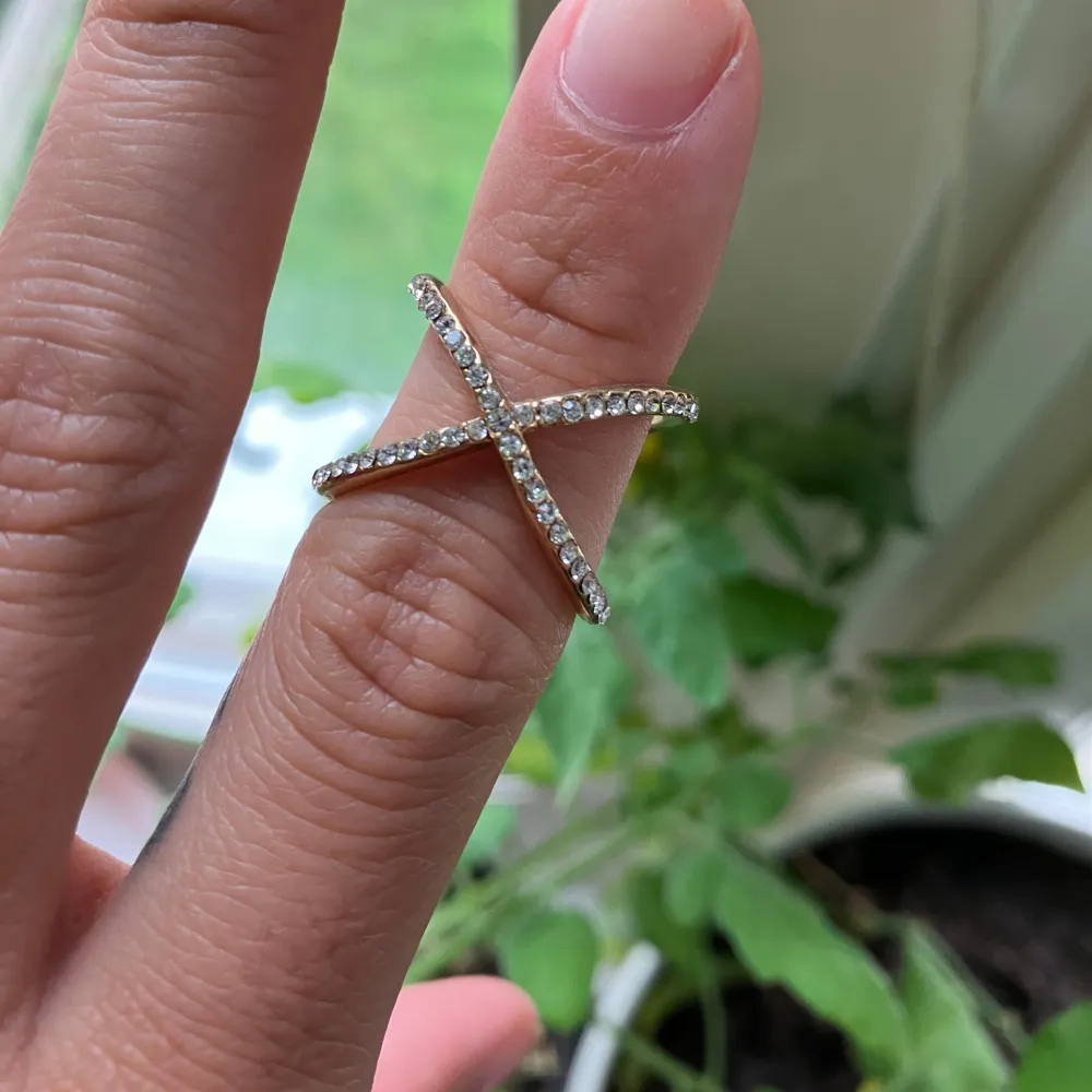 En ring som korsar sig själv, med strass. Accessoarer.