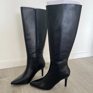 Svarta under knee boots - Säljer dessa stövlar med klack köpta från Nelly. Helt oanvända. Stl 36. Klackhöjd 7,5cm. Köpta för 799kr.