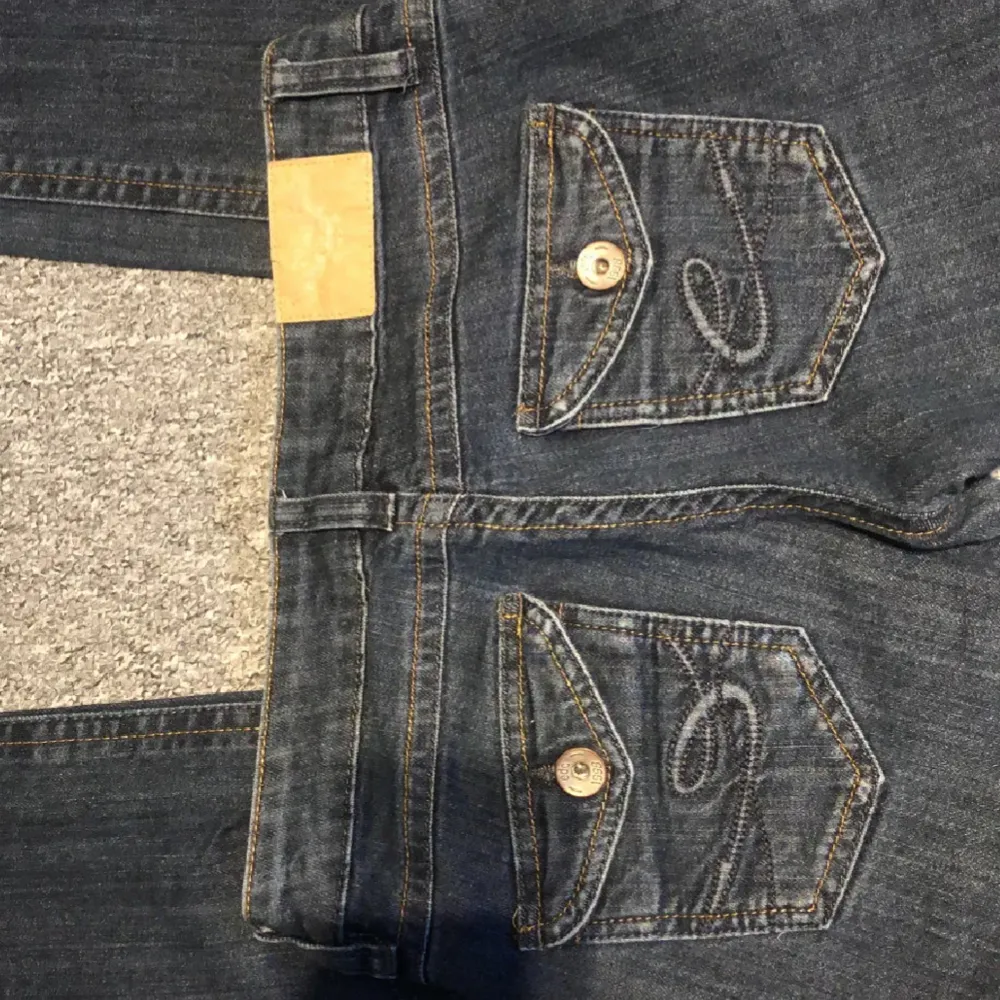 Säljer ett par snygga mörkblå bootcut jeans i lågmidjad stil. Bara användt ett fåtal gånger. De har en klassisk femficksdesign med knappar och dragkedja fram. Har sytt om dom från skinny till boothcut. Och valde att lägga in ett svart jeanstyg för snygg design. Pris kan diskuteras.. Jeans & Byxor.