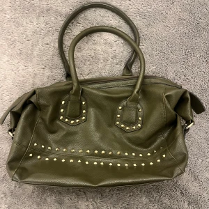 Grön väska - Jättecool grön handväska med guldiga nitar, som tyvärr inte kommer till användning. Jättefint skick och väldigt rymlig!