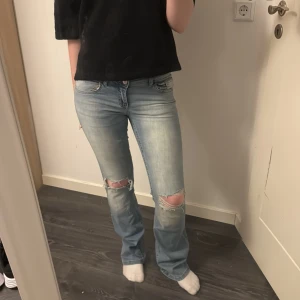 Ljusblå bootcut jeans - Säljer ett par ljusblå bootcut jeans i bra skick. De har snygga slitningar på knäna och en klassisk femficksdesign. Helt oanvända! 