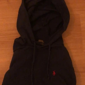 hoodie från Ralph Lauren - Säljer en snygg svart hoodie från Ralph Lauren i storlek S. Den har en klassisk design med en röd broderad logga på bröstet. Perfekt för både vardag och chill. Huvan är skön och tröjan har en normal passform. Hör av dig vid intresse! Mörk blå färg och tun men gör den unik och ser jätte bra ut