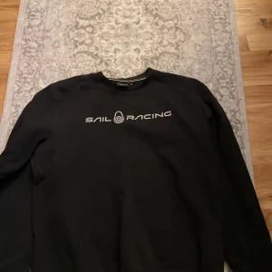 Svart tröja från Sail Racing - Säljer en svart tröja från Sail Racing i mycket bra skick. Den har en stilren design med logotypen tryckt på bröstet. Perfekt för både vardag och avslappnade tillfällen. Tröjan har långa ärmar och en normal passform. Passar bra till jeans eller chinos storleken är XL men passar som L pris kan diskuteras vid snabb affär.