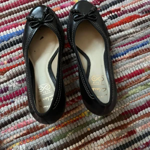 Svarta klackskor från Clarks - Säljer ett par eleganta svarta klackskor från Clarks i mycket bra skick. De har en söt rosett på tån och en bekväm klack. Perfekta för både vardag och fest!