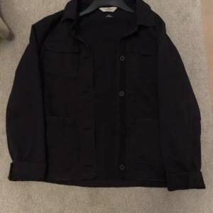 Overshirt från H&M - Säljer en stilren svart jacka från H&M i bra skick. Den har långa ärmar och knappar framtill. Skriv vid minsta lilla fundering✍️😀✅