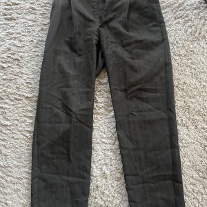 Acne Studios kostymbyxor  - Kostymbyxor från Acne Studios i bred rak passform. De är mörk bruna med ett rutigt mönster, storlek 44 men stora i storleken och passar någon som är 175cm enligt stprlekslappen. Jag är 175cm, 75kg och dessa passar mig, sitter ner som ett par 48or.  Byxorna är som nya!  Kan postas!  Hälsningar//  Ludvig