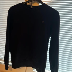 Svart tröja från mavi - Säljer en stilren svart tröja från mavi. Den har en enkel design med rund hals och långa ärmar, perfekt för både vardag . Tröjan är i bra skick och passar till det mesta i garderoben. Perfekt för höst och vinter!