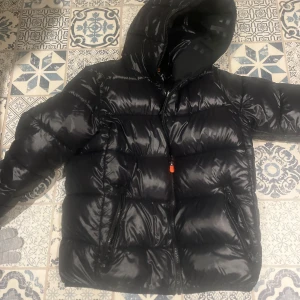 Svart pufferjacka med huva - Säljer en snygg svart pufferjacka i mycket bra skick. Den är perfekt för kalla vinterdagar och har en praktisk huva. Jackan har en dragkedja framtill och är quiltad för extra värme. Passar både till vardags och lite finare tillfällen. Perfekt för dig som vill hålla stilen i vinter! 🖤