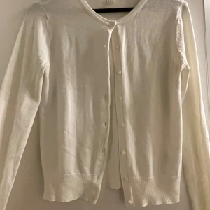 Vit kofta från H&M - Säljer en stilren vit kofta från H&M i storlek XS. Den är i bra skick och har långa ärmar med knappar framtill. Perfekt för både vardag och festliga tillfällen. Supermjuk och bekväm att ha på sig! 🤍