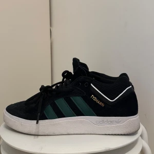 Svarta Adidas Skateboarding Tyshawn sneakers  - Säljer ett par  svarta Adidas Tyshawn sneakers i mocka. Använd en väldigt kort tid då jag skadade mig, väldigt lite slitage på höger fot, 