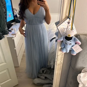 Ljusblå långklänning - Säljer en superfin ljusblå långklänning med smala axelband och v-ringning. Den är i nytt skick och har en öppen rygg som ger en extra touch! Den är perfekt till er som ska ta balen eller liknande! Tänkte ha denna på min bal men de stod mellan två, och därav prislapp kvar och helt oanvänd💖Köptes för 1200kr!