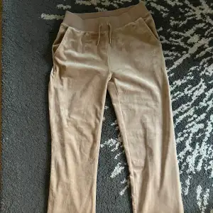 Säljer ett par superbekväma beige mjukisbyxor från Juicy Couture i storlek XS. Byxorna har en snygg glittrig Juicy-logga på baksidan och en elastisk midja med snörning. Har bara använts 1-2 gånger. Originalbild ifrån Juicys hemsida för att jämföra. Perfekta för en chill dag hemma eller en avslappnad utflykt. 🩶✨