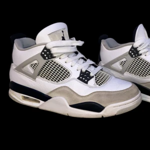 Nike Air Jordans 4 Military black - Säljer ett par klassiska Nike Air Jordans i vitt och svart. Skorna har en snygg design med nätpaneler och den ikoniska Jumpman-loggan på hälen. Perfekta för både vardag och sportiga tillfällen. De är i bra skick med lite slitage på sulan. Tillkommer låda och alla resterande saker som kom med skorna. Vid frågor så är det bara att höra av sig😃👍