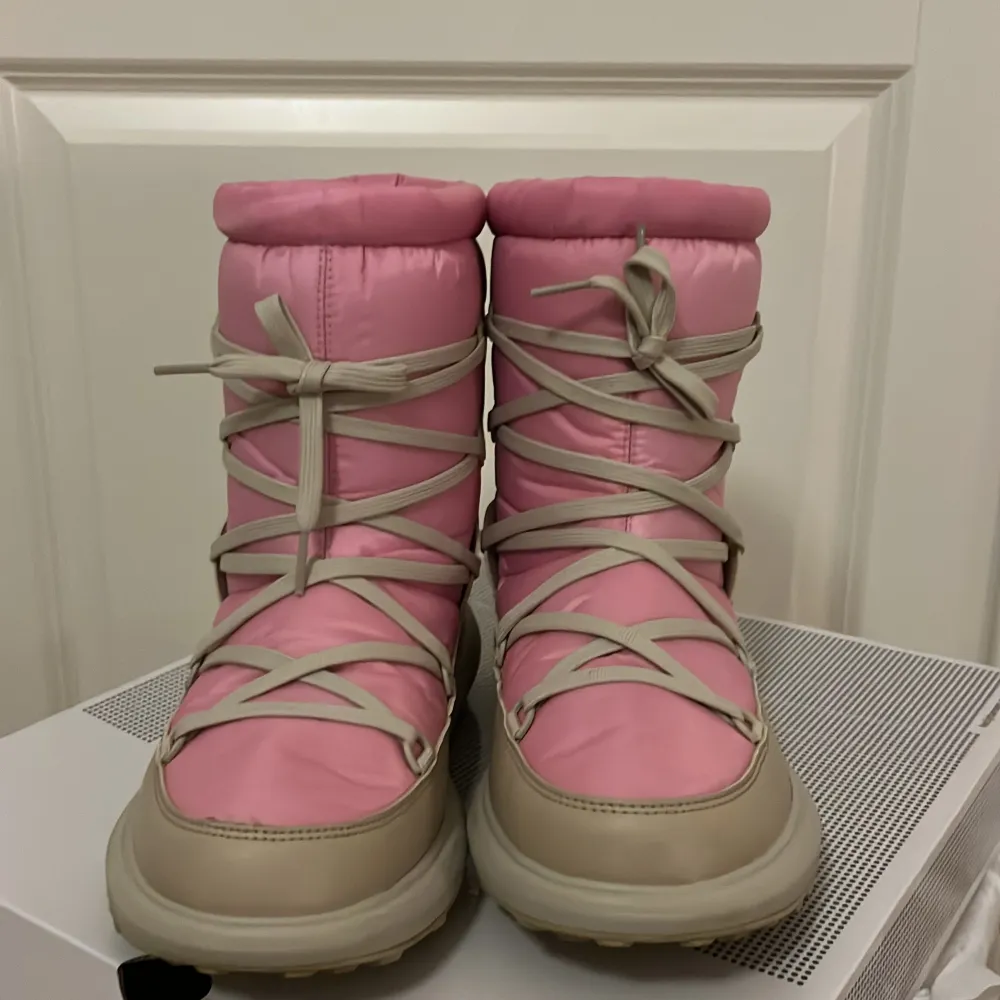 Säljer ett par supermysiga rosa och beige vinterstövlar från Helly Hansen. De har en vadderad design med snörning framtill och är perfekta för kalla vinterdagar. Stövlarna är i mycket bra skick och redo för nya äventyr i snön! ❄️ orginalpris 1700kr. Skor.