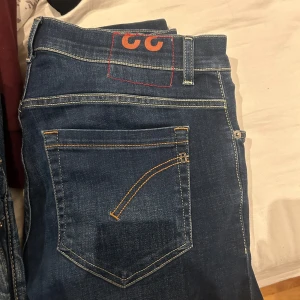 Dondup jeans  - Säljer ett par snygga blå jeans från Dondup i storlek 33. De har en klassisk femficksdesign med kontrasterande sömmar och en cool logga på baksidan. Perfekta för både vardag och fest! 🕺