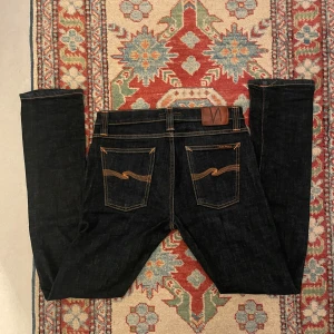 Nudie jeans ”Tube tom” - Säljer dessa nudie jeans i modellen ”tube tom”. Jeansen har skinny passform. Bra skick, lite färg på bakfickorna har bleknat. Mått är följande: midja, ca39cm. Ytterbenslängd, ca104cm. Benöppning ca16-17cm. Vad, ca 16 cm. Lår ifrån botten av grenen, ca 25-26cm. Fler bilder m.m går att fixa.
