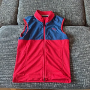 Röd och blå väst från Puma - Säljer en snygg röd och blå väst från Puma i mycket bra skick. Västen har en dragkedja framtill och är perfekt för träning eller som ett extra lager under höst och vår. Den är gjord av ett mjukt material som känns bekvämt mot huden. Pris går alltid att förhandlas!
