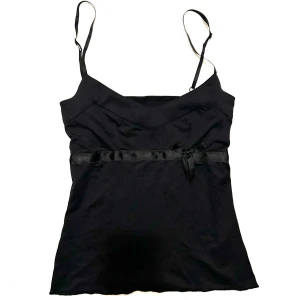 Svart satinlinne med rosett - Snyggt svart linne i satin med smala axelband och ett band med söt rosett under bröstet. Lite skadat i bandet men inget som syns. Storlek S.