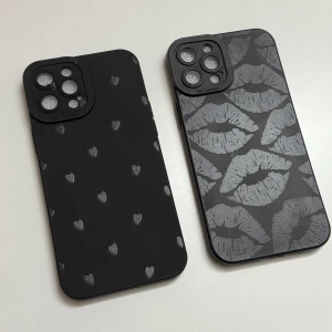 Svarta mobilskal med mönster av hjärtan och läppar - Två stiliga svarta mobilskal med unika mönster. Ett skal har små hjärtan och det andra har läppar i ett glansigt tryck. Perfekt för att ge din telefon en personlig touch och skydda den samtidigt. Helt oanvända, för iPhone 12 PRO Max. Passar utmärkt för både vardag och fest! 