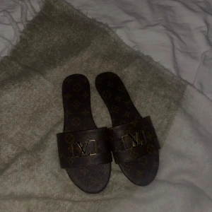 Bruna sandaler med monogram - Snygga bruna sandaler med det klassiska -monogrammet. Perfekta för sommardagar eller en avslappnad dag på stan. De har en öppen design och är superbekväma att bära. Ett måste för alla som älskar lyx och stil!