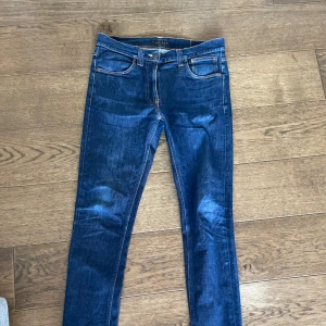 Nudie Jeans W33 L34 mörkblåa - Säljer ett par snygga mörkblå jeans från Nudie Jeans i storlek W33 L34. De har inga skador! Perfekta för både vardag och fest! 🕺priset är inte hugget i sten