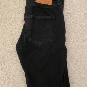 Svarta jeans från Levi's - Säljer ett par klassiska svarta Levi's 501 jeans i bra skick. De har en rak passform och är tillverkade i slitstarkt denim. Perfekta för både vardag och fest! 