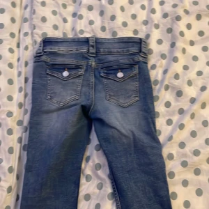 Blå jeans low waist Cn 160/69 200Kr - Säljer ett par snygga blå jeans i bra skick. De har en tight passform och är lågmidjade med dubbla knappar fram. Perfekta för vardagsbruk eller en utekväll. Jeansen har också snygga bakfickor med knappdetaljer.