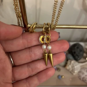 Guldörhängen med pärlor och spetsar - Snygga guldörhängen med cool design! De har små pärlor och spetsiga hängen som ger en edgy look. Perfekta för att piffa upp vilken outfit som helst, oavsett om det är till fest eller vardag. De är både eleganta och lite rockiga på samma gång.
