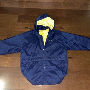 Vintage baggy Nike jacka  - Säljer en blå vintage jacka från Nike i mycket bra skick. Jackan har en gul/neon insida och en stor Nike-logga på ryggen. Dragkedja framtill och justerbar huva. Privat för mer info🐺