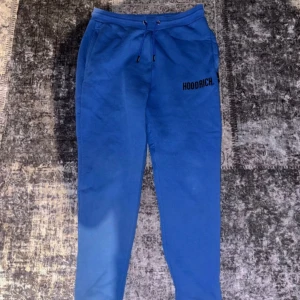 Blå mjukisbyxor från Hoodrich - Säljer ett par snygga blå mjukisbyxor från Hoodrich i storlek medium. De har en bekväm passform med snörning i midjan och en stilren logga på benet. Perfekta för chill dagar eller träning. Använda Max 5 gånger, inga fel på byxorna!