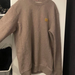 Beige tröja från Les Deux - Säljer en snygg beige tröja från Les Deux i storlek XS. Tröjan har en enkel design med en liten logga på bröstet och är i mycket bra skick. Perfekt för både höst och vår, och passar till det mesta i garderoben. Skön och stilren!