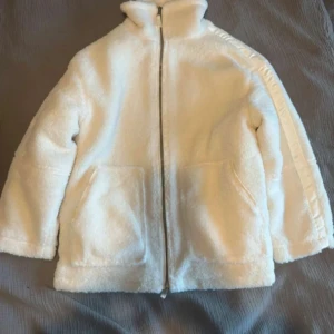 Vit teddyjacka  - Mysig vit teddyjacka i mycket bra skick. Perfekt för kyliga höst- och vinterdagar. Jackan har en dragkedja framtill och två stora fickor. Håller värmen väldigt bra, säljer då den var för stor. Helt oanvänd (lånade bilder) skriv för fler!