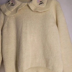 Gul stickad tröja från Pieces - Mysig beige stickad tröja från Pieces i storlek M. Den har en söt krage med broderade blommor i rosa och lila. Perfekt för höst och vinter, med långa ärmar och en bekväm passform. Superfin att ha på sig när det är kallt ute! 🌸
