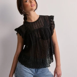 Svart transparent blus - Snygg svart transparent blus med korta ärmar och volangdetaljer. Perfekt för en kväll ute eller en fest. Blusen har ett randigt mönster och är lätt och luftig, vilket gör den idealisk för varmare väder.